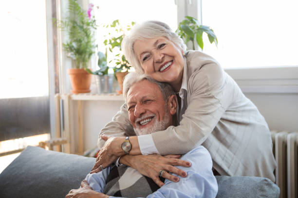 istock Woman embracing husband sitting on the sofa laughing 1306195681