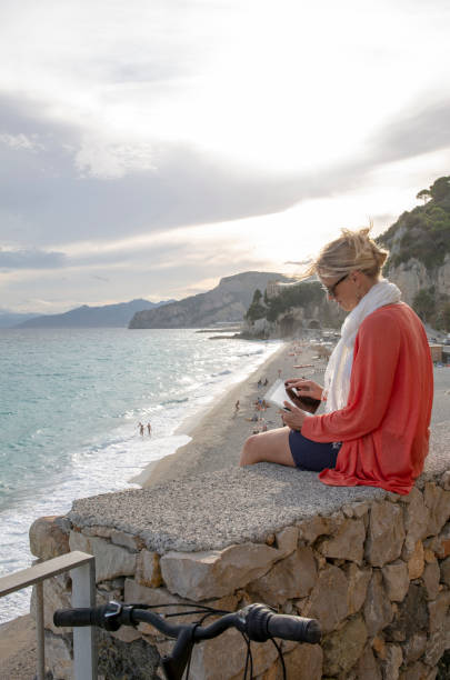 istock Woman sits on balcony above beach and uses digital tablet 1306197315