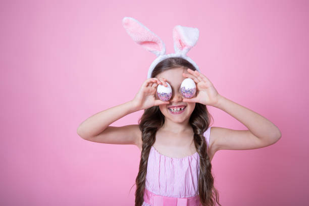 istock A funny little girl dressed in Easter bunny ears and in a dress posing with Easter eggs copy space. 1306198410