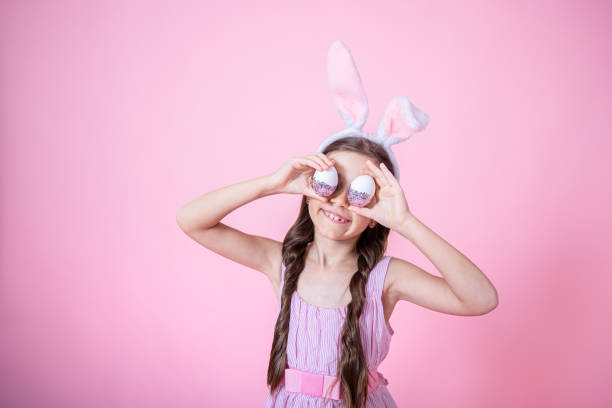 istock A beautiful little girl dressed in Easter bunny ears and in a dress posing with Easter eggs copy space. 1306198413
