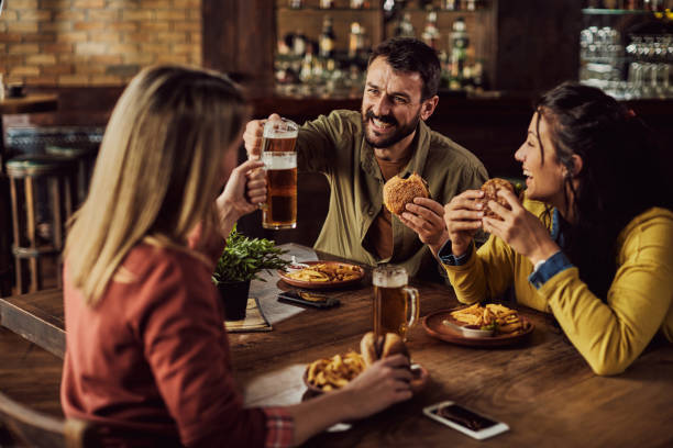 istock Happy friends having fun and toasting with beer while eating in a pub. 1306198426