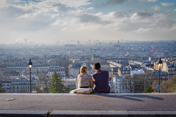 Paris, France: Montmartre district. Paris, France - 02 26 2021: Montmartre district. View of Paris from square Louise Michel and a young couple sitting on the steps montmartre stock pictures, royalty-free photos & images