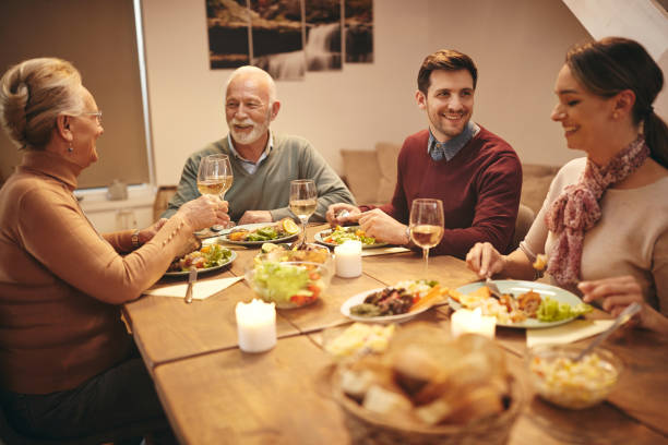 istock Happy family eating dinner and toasting with wine at dining table. 1306199830