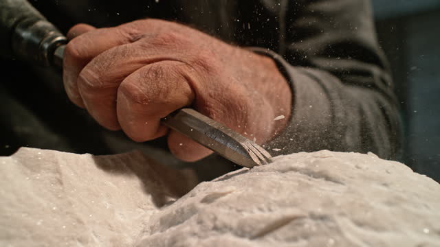 SLO MO LD Hand of male sculptor chiselling the surface of a white stone sculpture