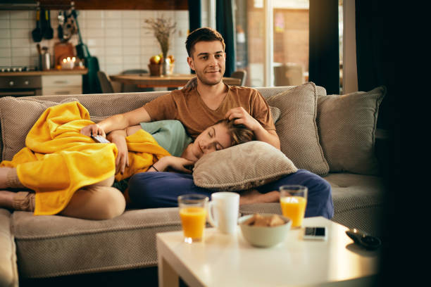 istock Happy man watching TV while girlfriend is taking a nap at home. 1306200832