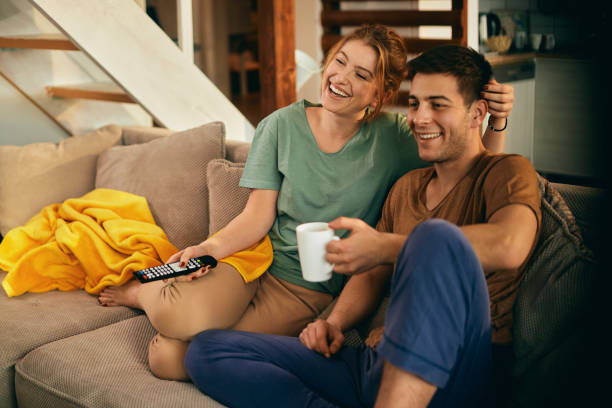 istock Young happy couple enjoying while watching TV and relaxing at home. 1306200876