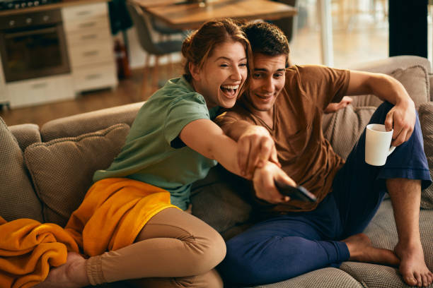 istock Young couple having fun while changing channels on a TV at home. 1306200947