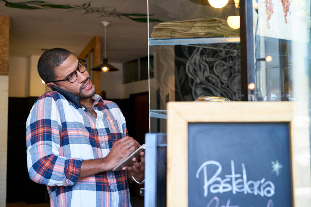 istock Portrait of young smiling man in coffee store using mobile phone 1306201061