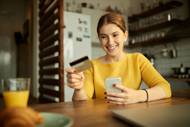 istock Happy woman using smart phone and credit card while e-banking at home. 1306201250