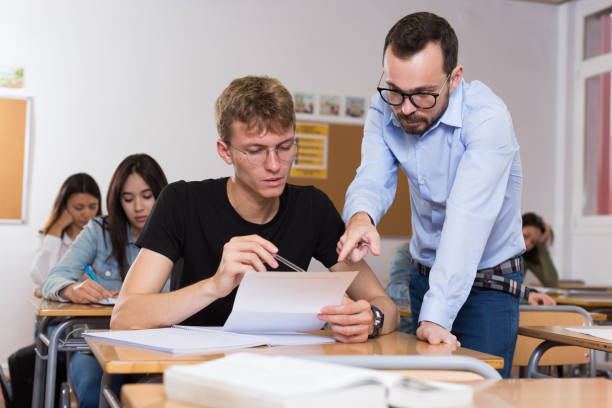 istock Young boy is writing test and teacher is explaining about questions 1306202260