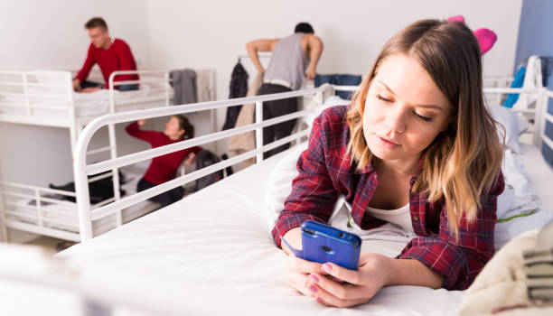 istock Woman lying on bed in hostel with phone 1306202474