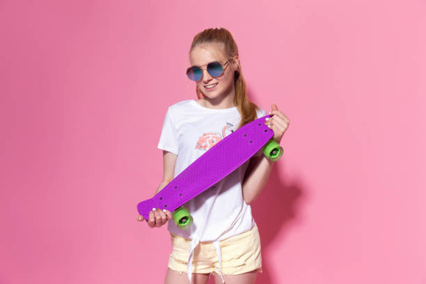 istock Cheerful young girl with a skateboard on the pink background 1306204309