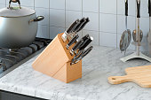 Kitchen knives with wooden block on the kitchen desk, 3D rendering