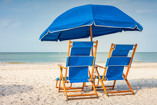 Beach with Lounge Chairs and Umbrella in Fort Myers, Florida, USA on a sunny day.
