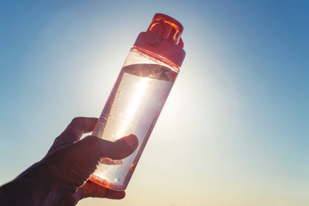 istock Man holding up a reusable water bottle in the sunshine. 1306209268