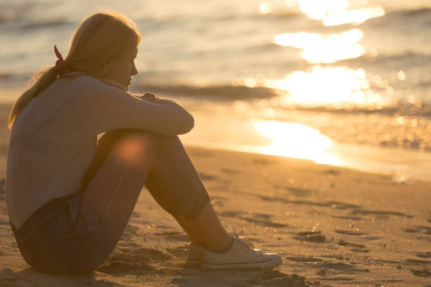 istock Relax woman sitting alone thinking at the beach during sunset. 1306209407