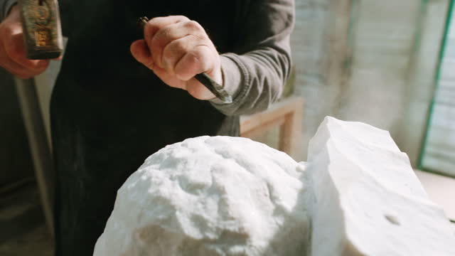 SLO MO Hands of male sculptor using a chisel carving a sculpture in his studio