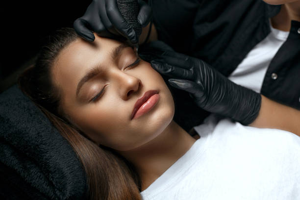 Beauty master making permanent brow makeup Beauty stylist making permanent brow makeup procedure at the cosmetic salon to a pretty young woman permanent marker photos stock pictures, royalty-free photos & images