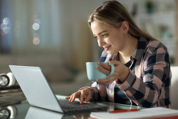 estudante e-learning usando laptop em casa durante a noite - registo no computador - fotografias e filmes do acervo