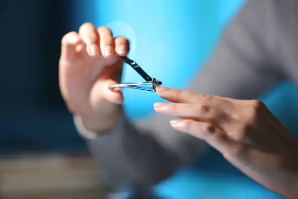 Woman hand cuting finger nails in the night