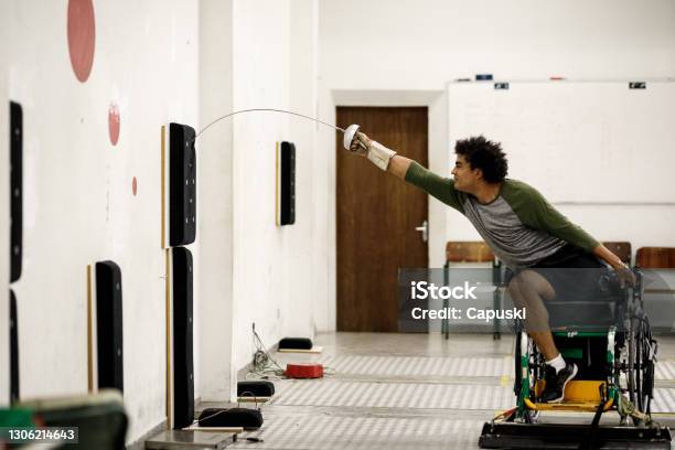 One Legged Male Wheelchair Fencing Athlete Training Lunge On Wall Equipment Stock Photo - Download Image Now