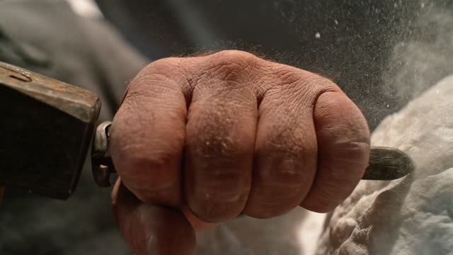 SLO MO LD Hand of a male sculptor holding a chisel while working