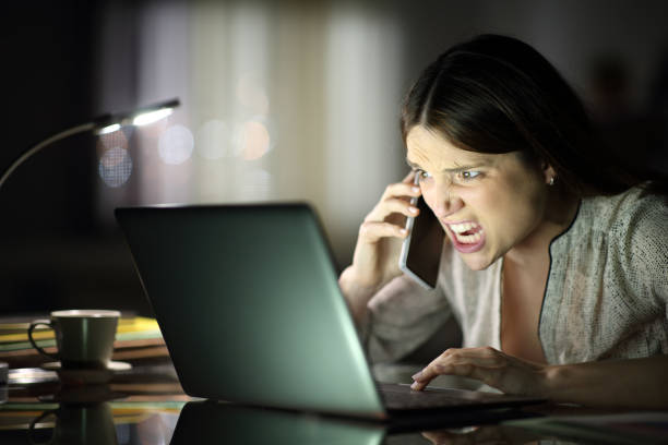 istock Angry freelancer talking on phone checking laptop in the night 1306225413