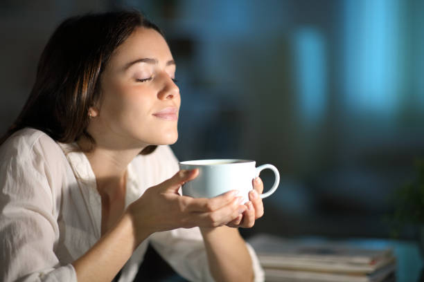 mujer oliendo café descafeinado en la noche - mujer bebiendo leche fotografías e imágenes de stock