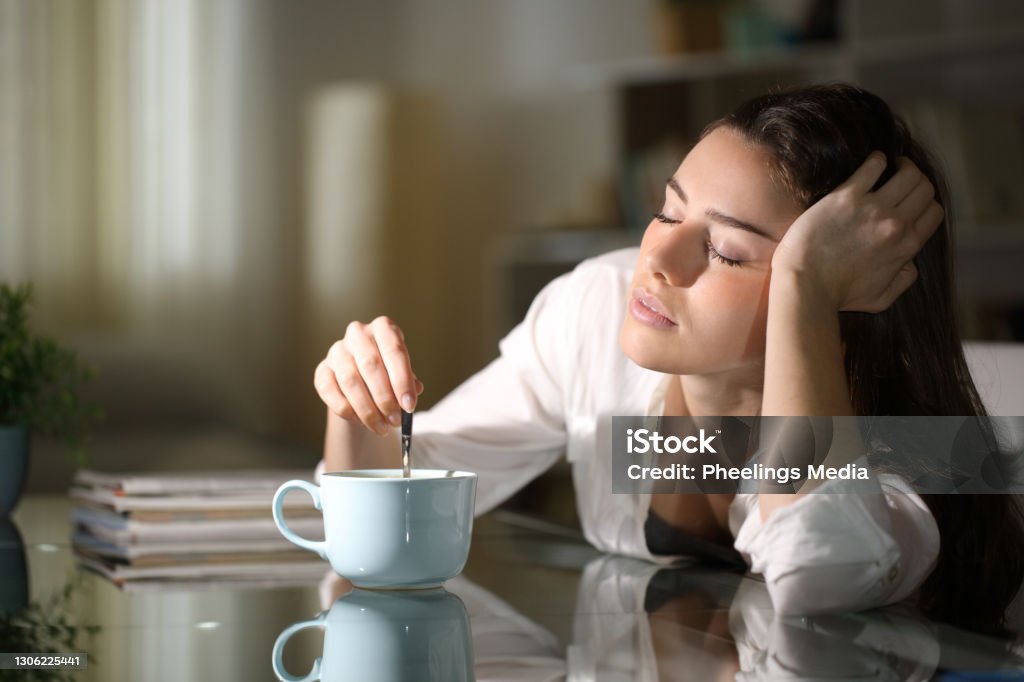 Sleepy woman stirring coffee in the morning Tired Stock Photo