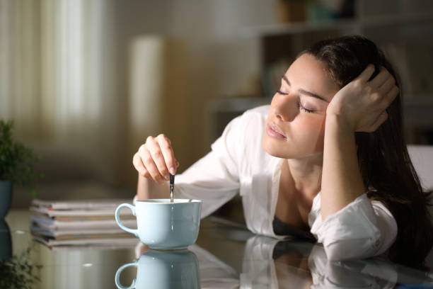 sleepy woman stirring coffee in the morning - exaustão imagens e fotografias de stock