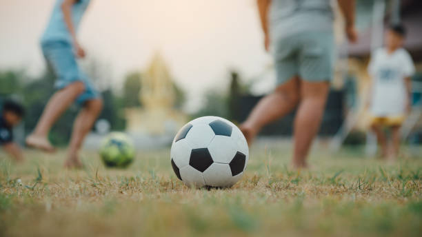 silhouette action sport im freien einer gruppe von kindern, die spaß beim spielen von straßenfußball für die ausübung in der gemeinde ländlichen bereich. arme und armutsarme kinder im entwicklungsland. - soccer teenager team ball stock-fotos und bilder