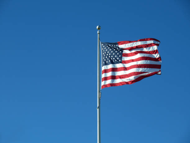 istock USA flag on flag pole with blue sky 1306229975