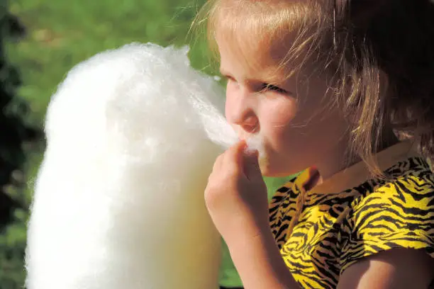 Soft focus of little girl  eating cotton candy in the park for a walk