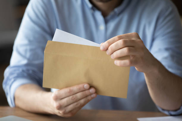 geschäftsmann nimmt brief aus umschlag mit geschäftsnachrichten - opening mail letter envelope stock-fotos und bilder