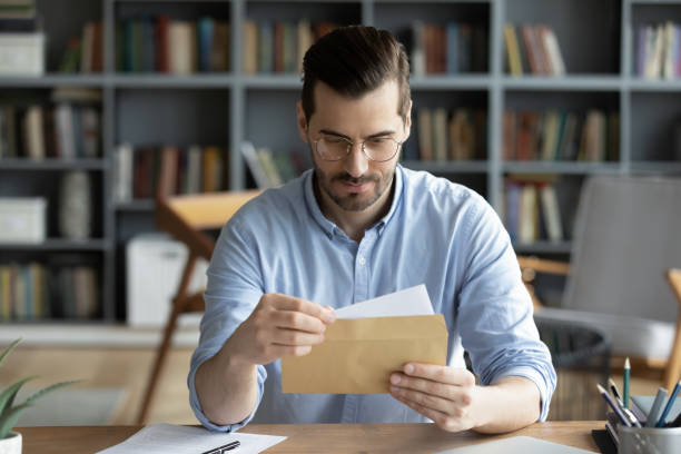 seriöser geschäftsmann sitzt am schreibtisch mit umschlag nehmen brief - opening mail letter envelope stock-fotos und bilder