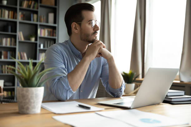 istock Pensive businessman sits at workplace desk look out the window 1306230738