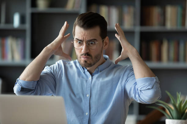 Employee looks at laptop feels angry having problems with device