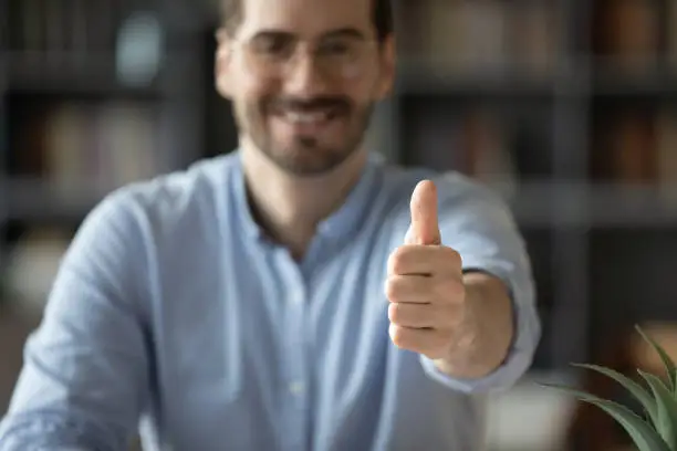 Photo of Happy man showing thumbsup, closeup focus on finger up