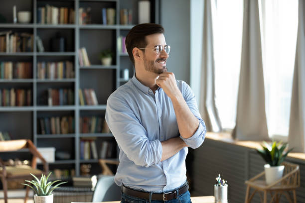 istock Confident happy businessman standing in modern office and thinking 1306230803