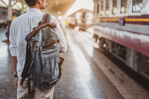 Asian man traveler with backpack in the railway, Backpack at the train station with a traveler. Travel concept. Man traveler tourist walking at train station.