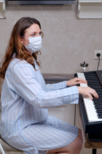 istock A woman in a face mask plays a home digital piano, problems with learning music during a period of isolation in quarantine 1306230956