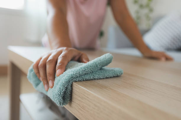 Woman cleaning and wiping the table with microfiber cloth in the living room. Woman doing chores at home. stock photo
