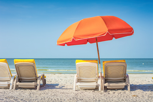 Beach with Lounge Chairs and Umbrella in Fort Myers, Florida, USA on a sunny day.