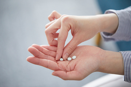 Woman hand takes vitamin B12  from medicine container