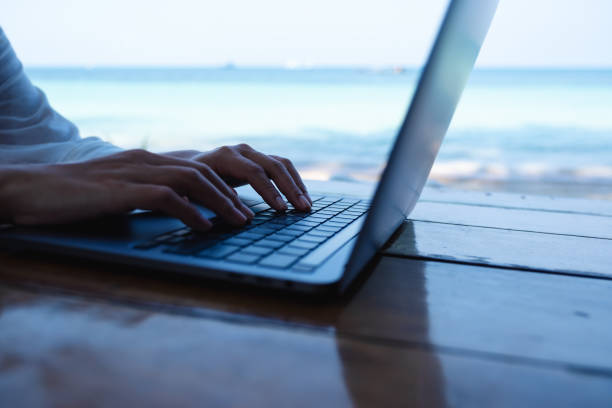 istock a woman working and typing on laptop computer on the beach 1306235574