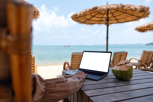 istock a woman using and touching on laptop touchpad with blank desktop screen while sitting on the beach 1306235575