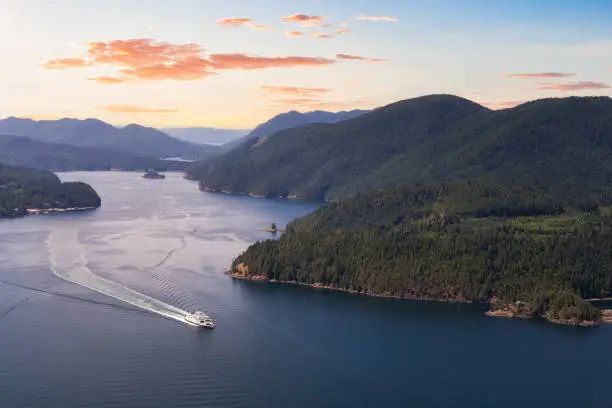 Aerial view of the Ferry traveling between the islands during a sunny summer evening. Sunset Sky Art Render. Taken in Sunshine Coast, BC, Canada.