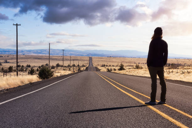 Man is standing in the middle of the long road.