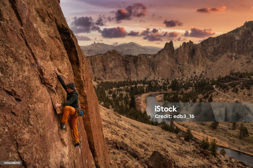 El hombre aventurero está escalando en roca en el lado de un acantilado empinado. - Foto de stock de Escalada libre de derechos