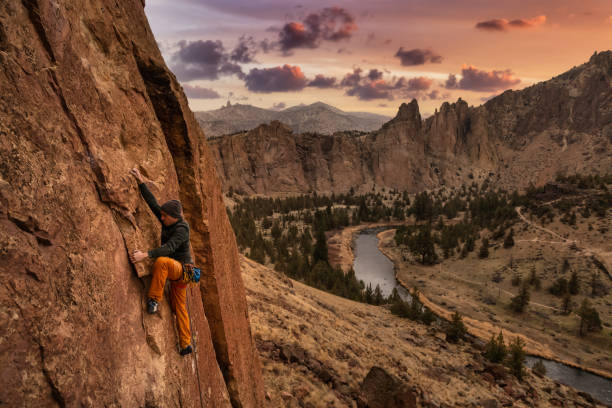 Adventurous man is rock climbing on the side of a steep cliff.